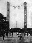 Az olimpiai láng megérkezik a berlini stadionba. Háttérben a marathoni kapu