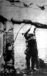Egy német műszaki katona kábelkötéss próbál megrögzíteni egy ingadozó épületromot