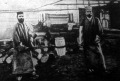 A Krupp-gyárban két nagyerejü munkás az ágyuanyaghoz szükséges bronzkeveréket izzó fehér állapotban szállitja a hűtőbe A Krupp-gyárban két nagyerejü munkás az ágyuanyaghoz szükséges bronzkeveréket izzó fehér állapotban szállitja a hűtőbe